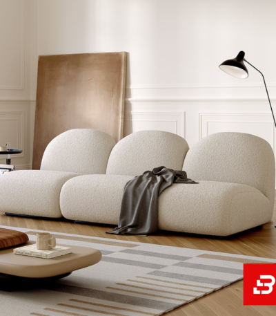 Elegant modern minimalist living room interior showcasing a modular bubble sofa upholstered in textured off white bouclé fabric featuring rounded organic backrests and a dark throw blanket by Bahoo Furniture UAE