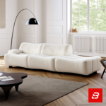 Bright sunlit modern minimalist living room interior showcasing a luxury ribbed lounge sofa upholstered in textured off white bouclé fabric featuring distinct vertical channel tufting and a sleek arch floor lamp by Bahoo Furniture UAE