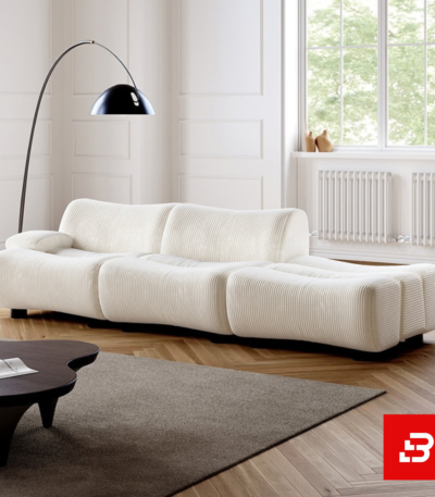Bright sunlit modern minimalist living room interior showcasing a luxury ribbed lounge sofa upholstered in textured off white bouclé fabric featuring distinct vertical channel tufting and a sleek arch floor lamp by Bahoo Furniture UAE