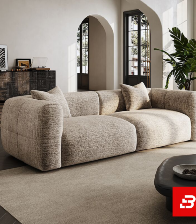 Sunlit luxury living room interior showcasing a spacious deep-seat sofa upholstered in textured warm gray bouclé fabric featuring wide track arms, plush back cushions, and accent pillows by Bahoo Furniture UAE