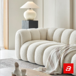 Sunlit modern minimalist living room interior showcasing a luxury ribbed sofa upholstered in textured off white bouclé fabric featuring distinct vertical channel tufting and continuous curved lines by Bahoo Furniture UAE