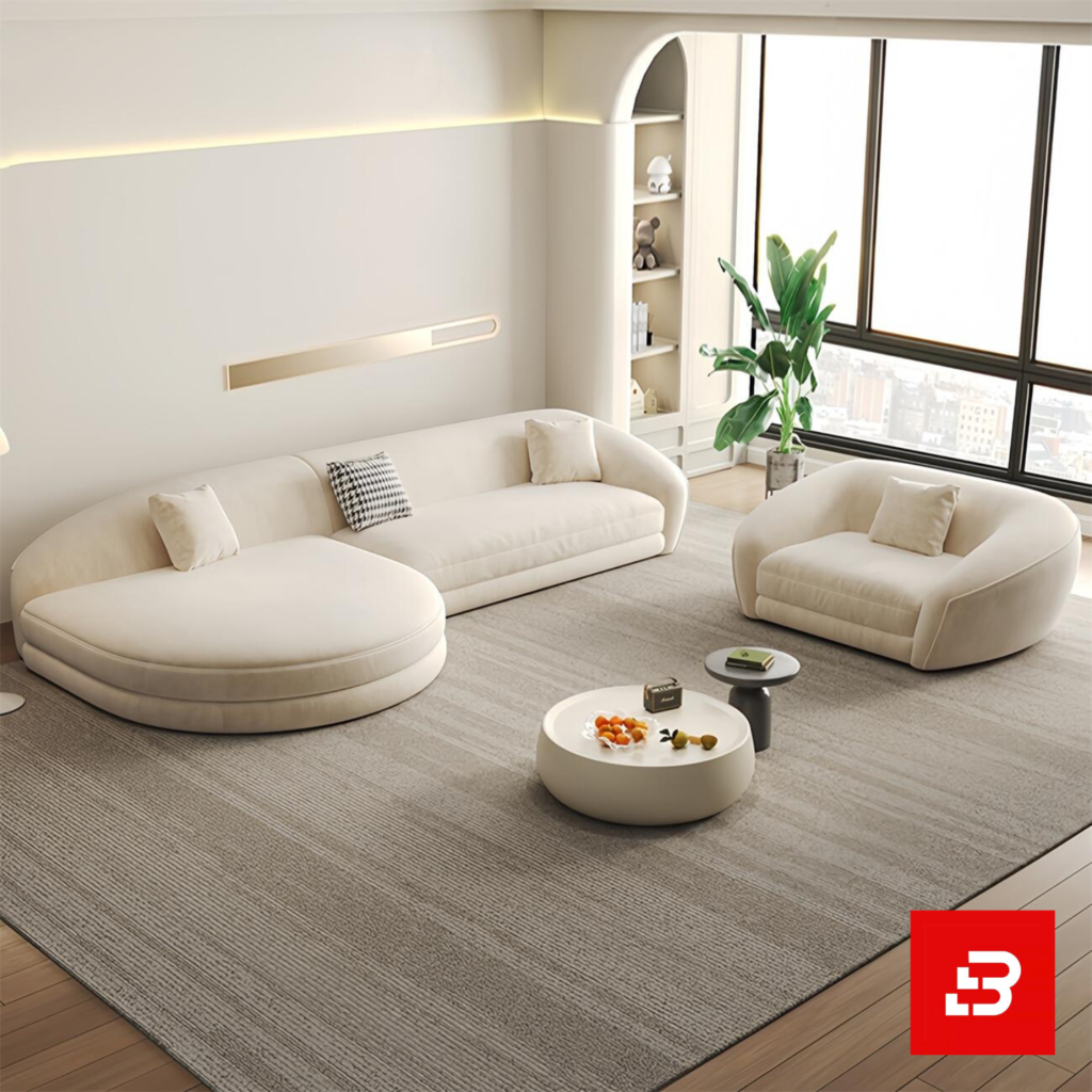 Sunlit luxury living room interior showcasing a sprawling curved chaise lounge sofa and matching armchair upholstered in textured off white bouclé fabric featuring sweeping rounded contours and a round coffee table by Bahoo Furniture UAE