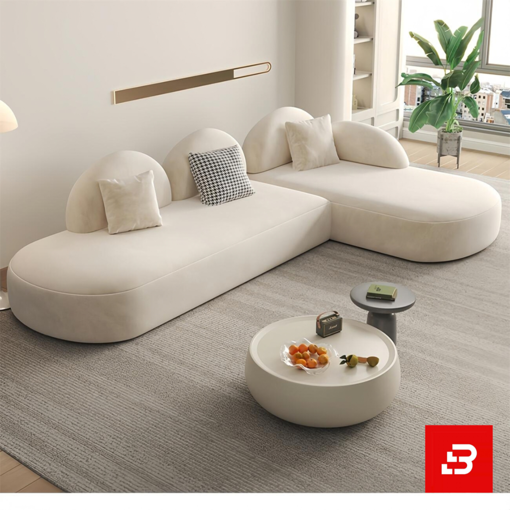 Bright modern minimalist living room interior showcasing an L-shaped modular sectional sofa upholstered in textured off white bouclé fabric featuring distinct half-moon backrests and accent pillows by Bahoo Furniture UAE