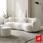 Sunlit modern minimalist living room interior showcasing a luxury curved sofa upholstered in textured off white bouclé fabric featuring sweeping rounded armrests and matching throw pillows by Bahoo Furniture UAE