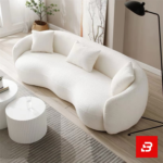 Sunlit modern minimalist living room interior showcasing a luxury curved sofa upholstered in textured off white bouclé fabric featuring sweeping rounded armrests and matching throw pillows by Bahoo Furniture UAE