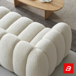 Sunlit modern minimalist living room interior showcasing a luxury ribbed sofa upholstered in textured off white bouclé fabric featuring distinct vertical channel tufting and continuous curved lines by Bahoo Furniture UAE