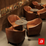 Upscale ambient lounge interior showcasing luxury round club armchairs upholstered in rich beige leather surrounding small round tables by Bahoo Furniture UAE