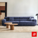 Modern minimalist living room interior showcasing a luxury modular sofa upholstered in deep warm gray bouclé fabric featuring low-profile cushions and matching wooden coffee tables by Bahoo Furniture UAE