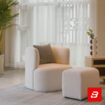 Bright modern living room interior showcasing a luxury accent armchair and matching ottoman upholstered in soft off white bouclé fabric featuring a decorative checkered throw pillow by Bahoo Furniture UAE
