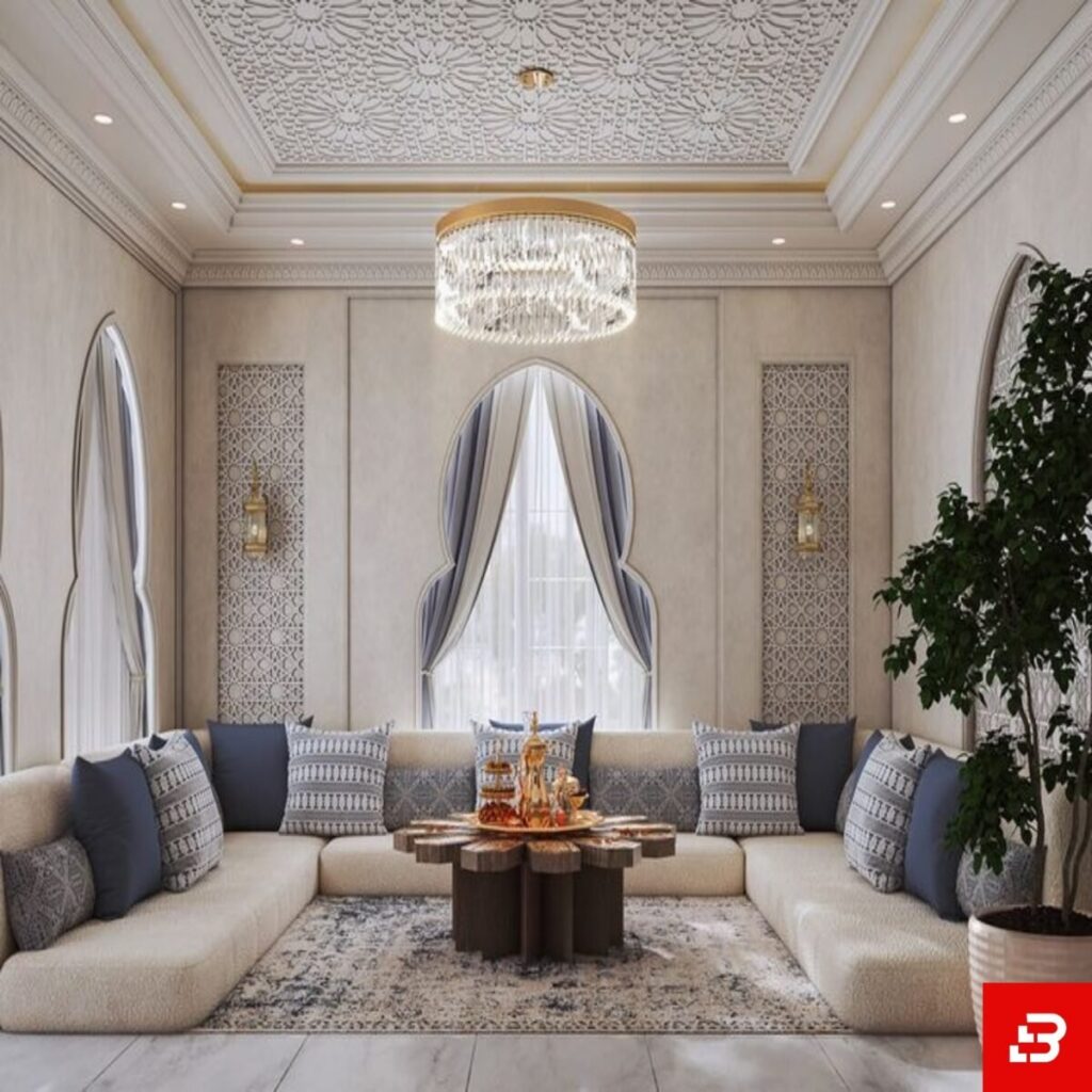 Front interior view of a luxury upholstered modern majlis sectional sofa in beige velvet fabric featuring blue accent cushions and an ornate wooden coffee table by Bahoo Furniture UAE
