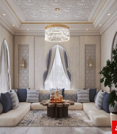 Front interior view of a luxury upholstered modern majlis sectional sofa in beige velvet fabric featuring blue accent cushions and an ornate wooden coffee table by Bahoo Furniture UAE