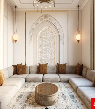 Eye-level interior view of a luxury upholstered arabic majlis sectional sofa in warm gray velvet fabric featuring brown accent pillows and an ornate arched wall feature by Bahoo Furniture UAE