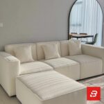 Modern living room interior view of a luxury upholstered contemporary sectional sofa and movable ottoman in off white bouclé fabric with matching throw pillows by Bahoo Furniture UAE
