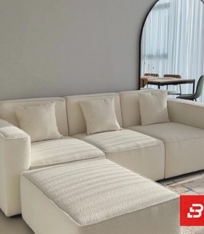 Modern living room interior view of a luxury upholstered contemporary sectional sofa and movable ottoman in off white bouclé fabric with matching throw pillows by Bahoo Furniture UAE
