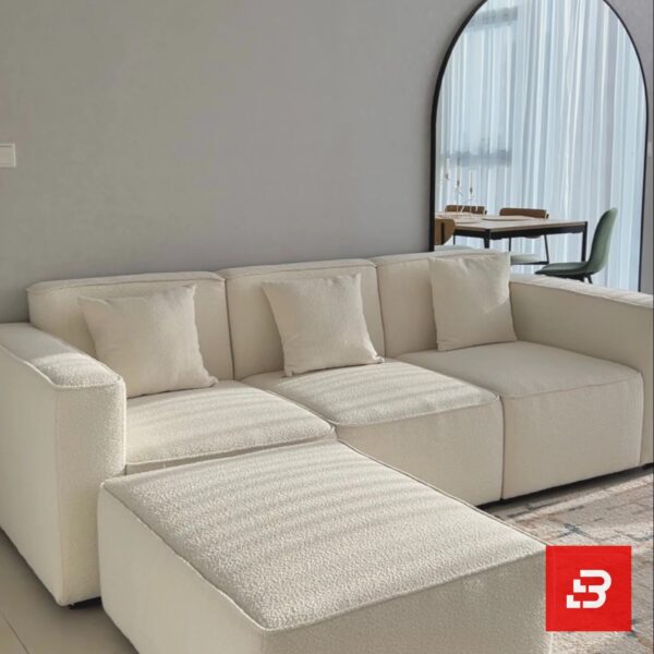 Modern living room interior view of a luxury upholstered contemporary sectional sofa and movable ottoman in off white bouclé fabric with matching throw pillows by Bahoo Furniture UAE