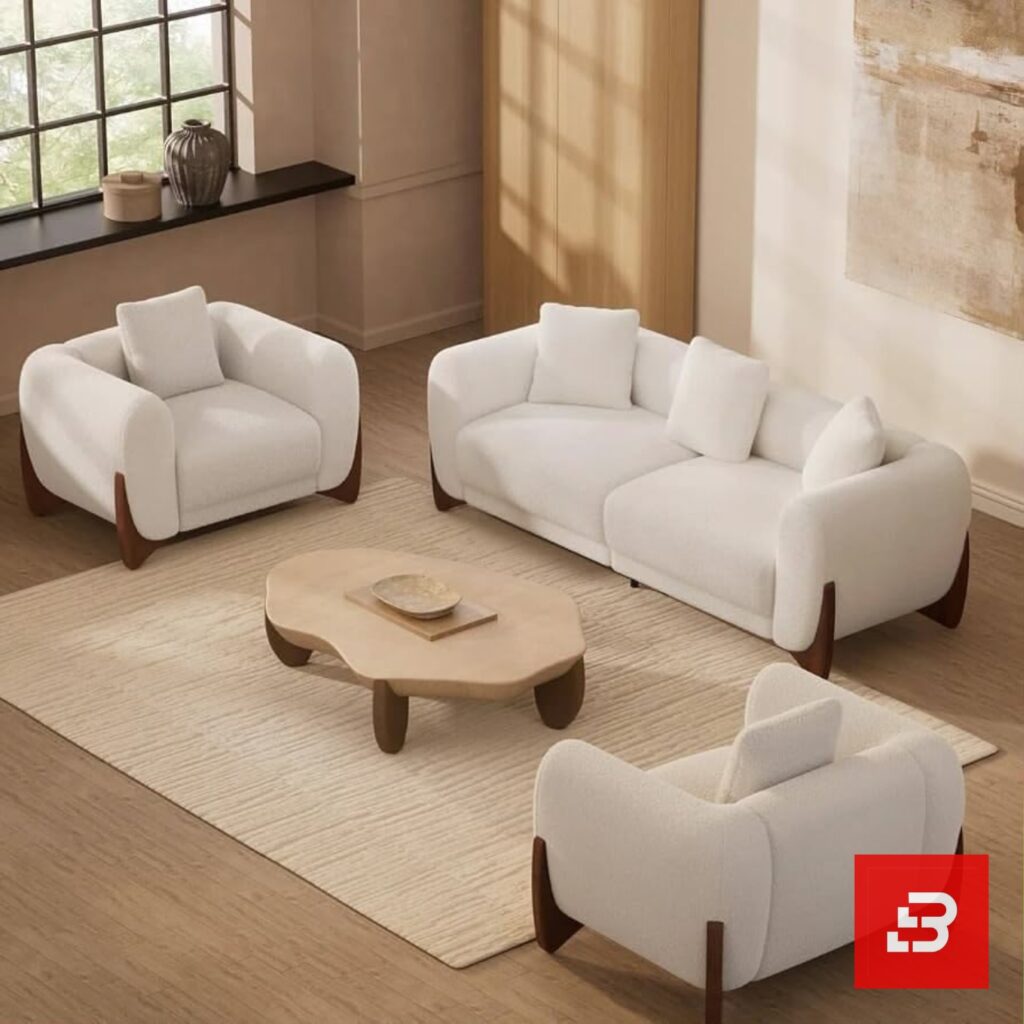 Stylized living room interior view of a luxury upholstered contemporary sofa set featuring a 3-seater sofa and two matching armchairs in off white bouclé fabric with dark wooden base accents by Bahoo Furniture UAE