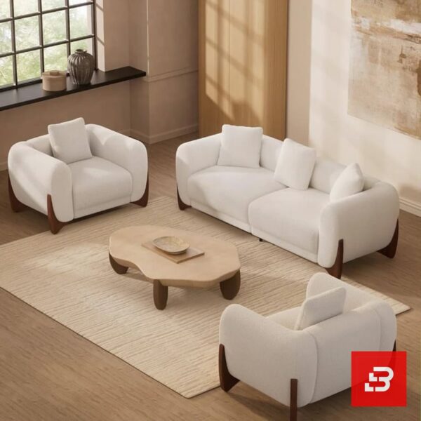 Stylized living room interior view of a luxury upholstered contemporary sofa set featuring a 3-seater sofa and two matching armchairs in off white bouclé fabric with dark wooden base accents by Bahoo Furniture UAE