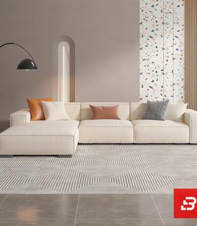 Modern living room interior view of a luxury upholstered chaise sectional sofa in smooth beige leather fabric with an extended chaise lounge and accent throw pillows by Bahoo Furniture UAE