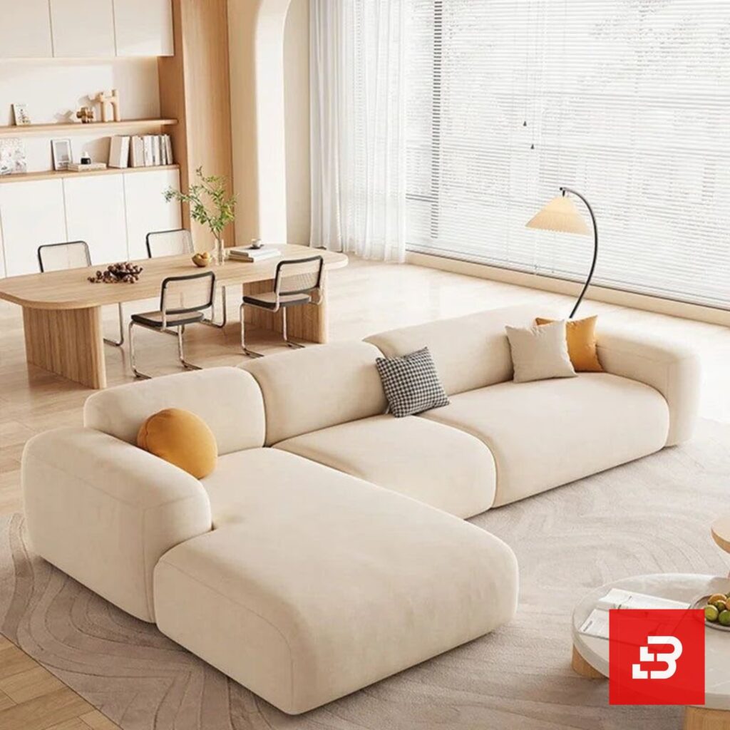 Modern living room interior view of a luxury upholstered contemporary sectional sofa with a plush chaise lounge and accent pillows in off white bouclé fabric by Bahoo Furniture UAE