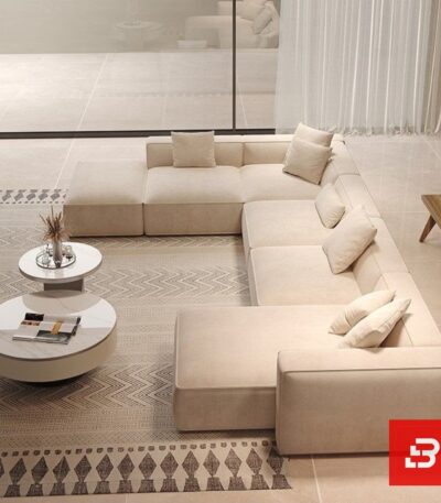 High-angle interior view of a luxury upholstered grand modular sectional sofa in beige velvet fabric featuring dual chaise extensions and accent pillows by Bahoo Furniture UAE