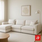 Modern living room interior view of a luxury upholstered chaise sectional sofa in textured off white bouclé fabric with an extended chaise lounge and accent pillows by Bahoo Furniture UAE