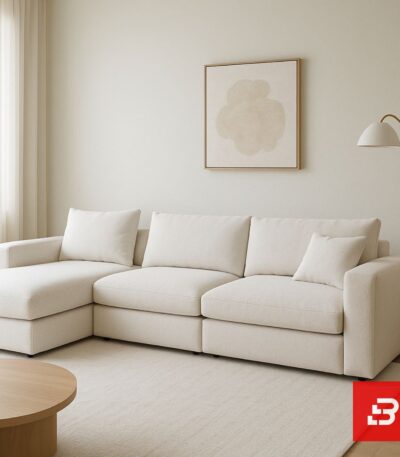 Modern living room interior view of a luxury upholstered chaise sectional sofa in textured off white bouclé fabric with an extended chaise lounge and accent pillows by Bahoo Furniture UAE
