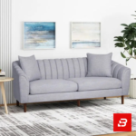 Sophisticated modern living room interior showcasing a luxury channel-tufted sofa upholstered in soft off white textured fabric featuring vertical back channeling and wooden tapered legs by Bahoo Furniture UAE