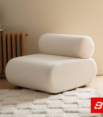 Minimalist living room setup showcasing a plush off white bouclé modular lounge chair with bolster backrest on a checkered textured rug by Bahoo Furniture UAE