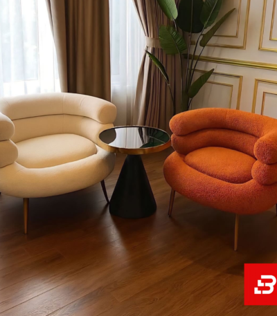 Elegant interior showcasing a luxury off white bouclé curved armchair paired with a stylish glass top side table on dark hardwood flooring by Bahoo Furniture UAE