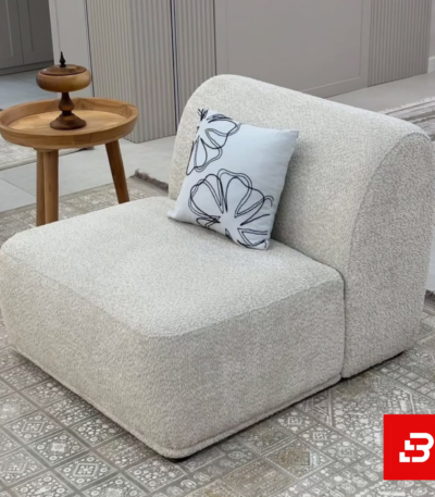 Modern elegant living space featuring a low-profile off white bouclé modular armless lounge chair styled with an embroidered cushion and wooden side table by Bahoo Furniture UAE