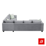 Bright and airy modern living room interior showcasing a large l-shape sectional sofa upholstered in soft warm gray fabric with pastel green throw pillows and a glass coffee table by Bahoo Furniture UAE