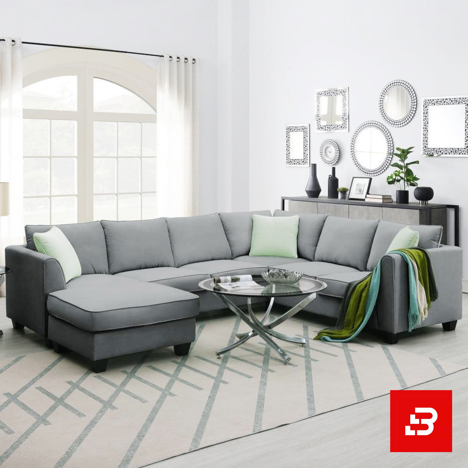 Bahoo Luxury L-Shape Sectional Sofa Upholstered - Bahoo Furniture Bright and airy modern living room interior showcasing a large l-shape sectional sofa upholstered in soft warm gray fabric with pastel green throw pillows and a glass coffee table by Bahoo Furniture UAE