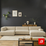 Sophisticated dark interior setting showcasing an expansive beige fabric u-shape sectional sofa against dark grey walls, framed art, and wooden flooring by Bahoo Furniture UAE