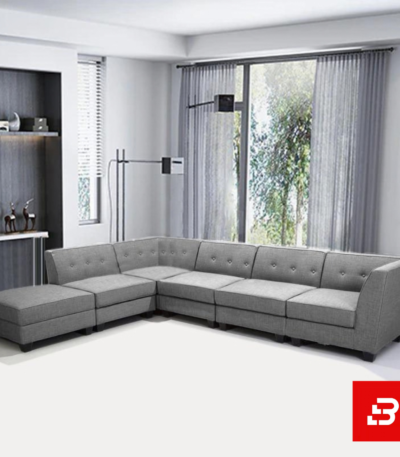 Modern contemporary living room featuring a warm gray fabric button-tufted l-shape sectional sofa set with a matching ottoman and minimalist shelves by Bahoo Furniture UAE