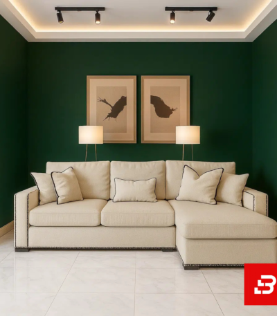Elegant living room interior with deep green walls showcasing a beige fabric l-shape sectional sofa with contrast piping trim, matching scatter cushions, and framed artwork by Bahoo Furniture UAE