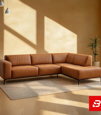 Sunlit modern living room interior showcasing a beige leatherette l-shape sectional sofa with vertical channel tufting, slim black metal legs, and warm minimalist wall lighting by Bahoo Furniture UAE