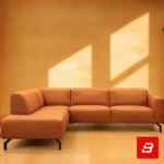 Sunlit modern living room interior showcasing a beige leatherette l-shape sectional sofa with vertical channel tufting, slim black metal legs, and warm minimalist wall lighting by Bahoo Furniture UAE