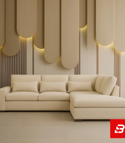 Modern minimalist living room interior showcasing a beige fabric l-shape sectional sofa with matching bolster pillows against a vertical wood panel accent wall with warm lighting by Bahoo Furniture UAE
