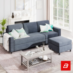 Bright modern living room interior showcasing a warm gray fabric l-shape sectional sofa with matching footrest ottoman, patterned botanical scatter pillows, a wooden coffee table, and a fireplace mantel by Bahoo Furniture UAE