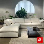 Serene modern luxury living room interior showcasing a plush l-shape sectional sofa upholstered in soft off white fabric paired with a matching chaise lounge and indoor botanical plants by Bahoo Furniture UAE