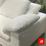 Serene modern luxury living room interior showcasing a plush l-shape sectional sofa upholstered in soft off white fabric paired with a matching chaise lounge and indoor botanical plants by Bahoo Furniture UAE