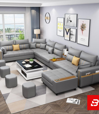 Sleek modern luxury living room interior showcasing an extensive modular sectional sofa upholstered in soft warm gray fabric featuring integrated armrest storage pockets and matching ottomans by Bahoo Furniture UAE